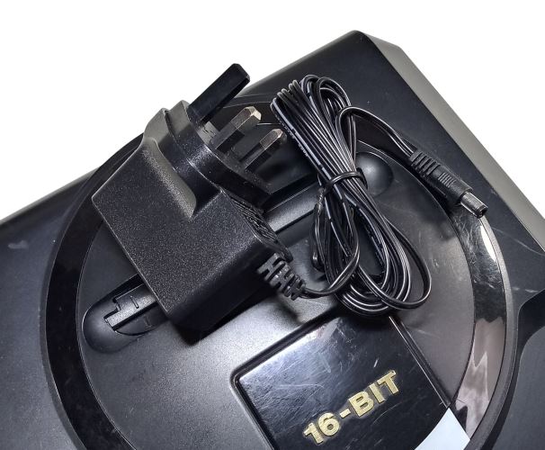 Regulated power supply for Sega Mega Drive / Genesis 1 with UK plug on top of the console